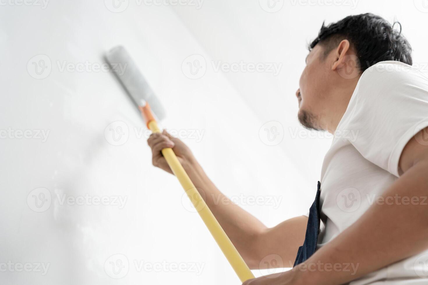 painter man, brush in hand for products to restore and paint the wall, indoor the building site of a house, wall during painting, renovation, painting, contractor, Architect, construction worker. photo