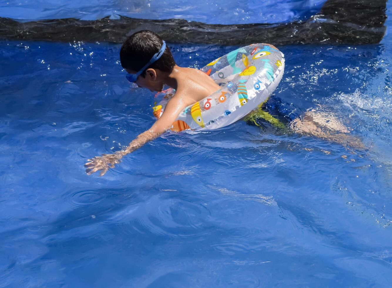A boy swimming in a pool with an inflatable ring photo