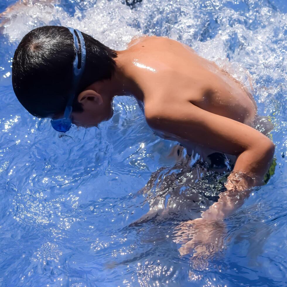 A young boy in a swimming pool with goggles on photo