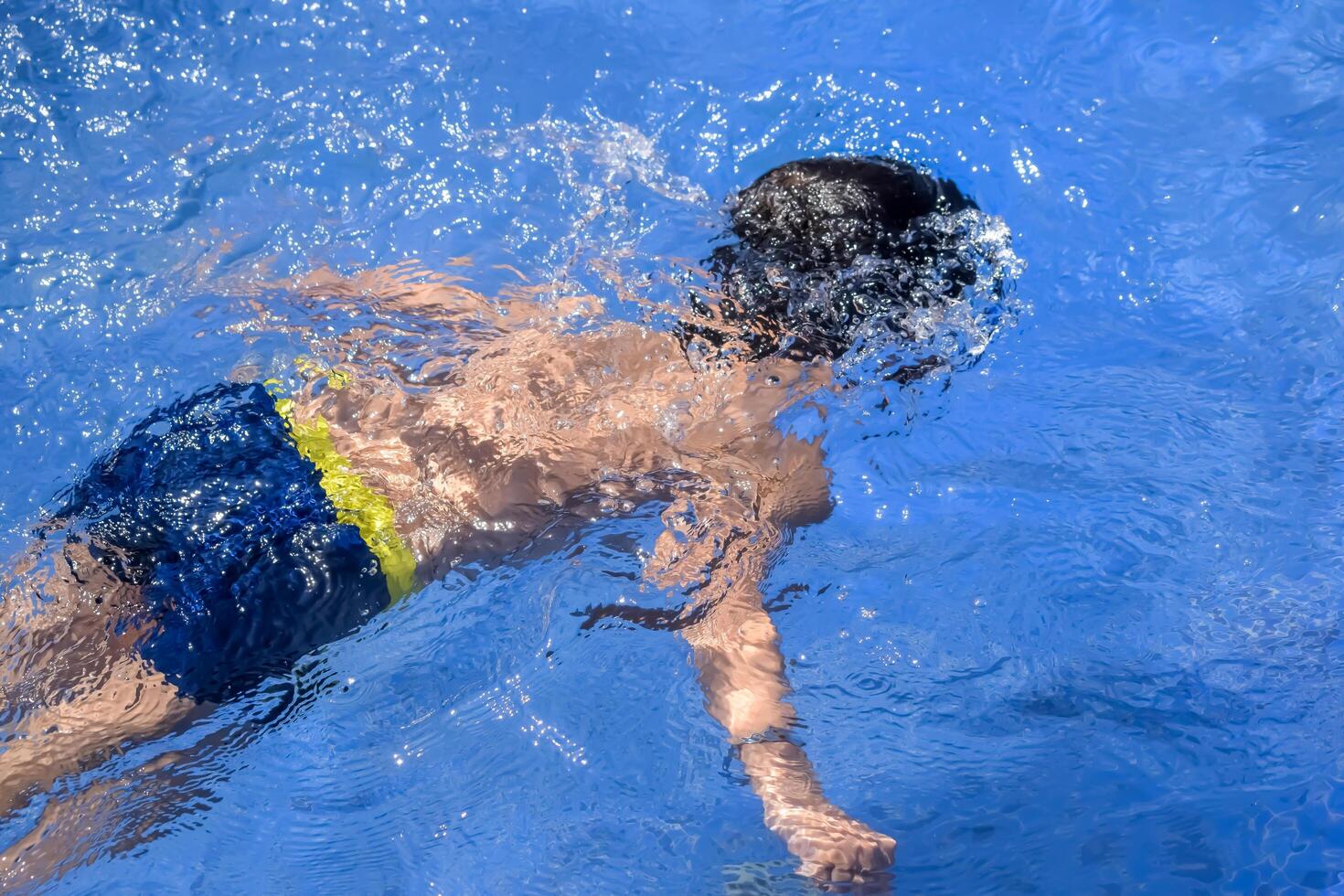 A child swimming in a pool with water splashing photo