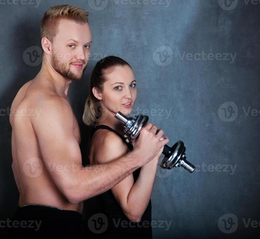 Athletic couple with a dumbells near the wall photo