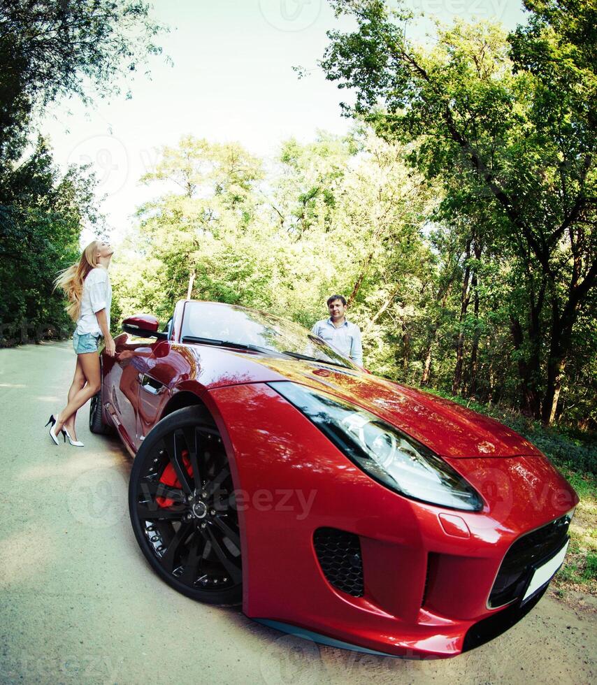Young happy couple standing near red sport car photo