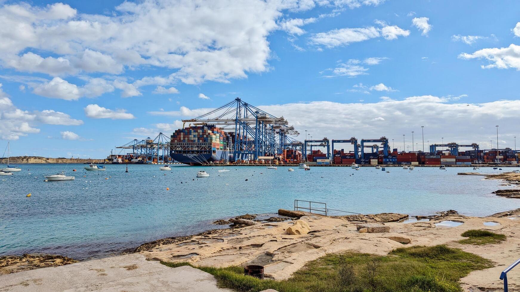Busy waterfront showcases massive cranes above freeport brimming with stacked containers, freeport fostering global trade expansion. Birzebbuga, Malta - 01.12.2024 photo