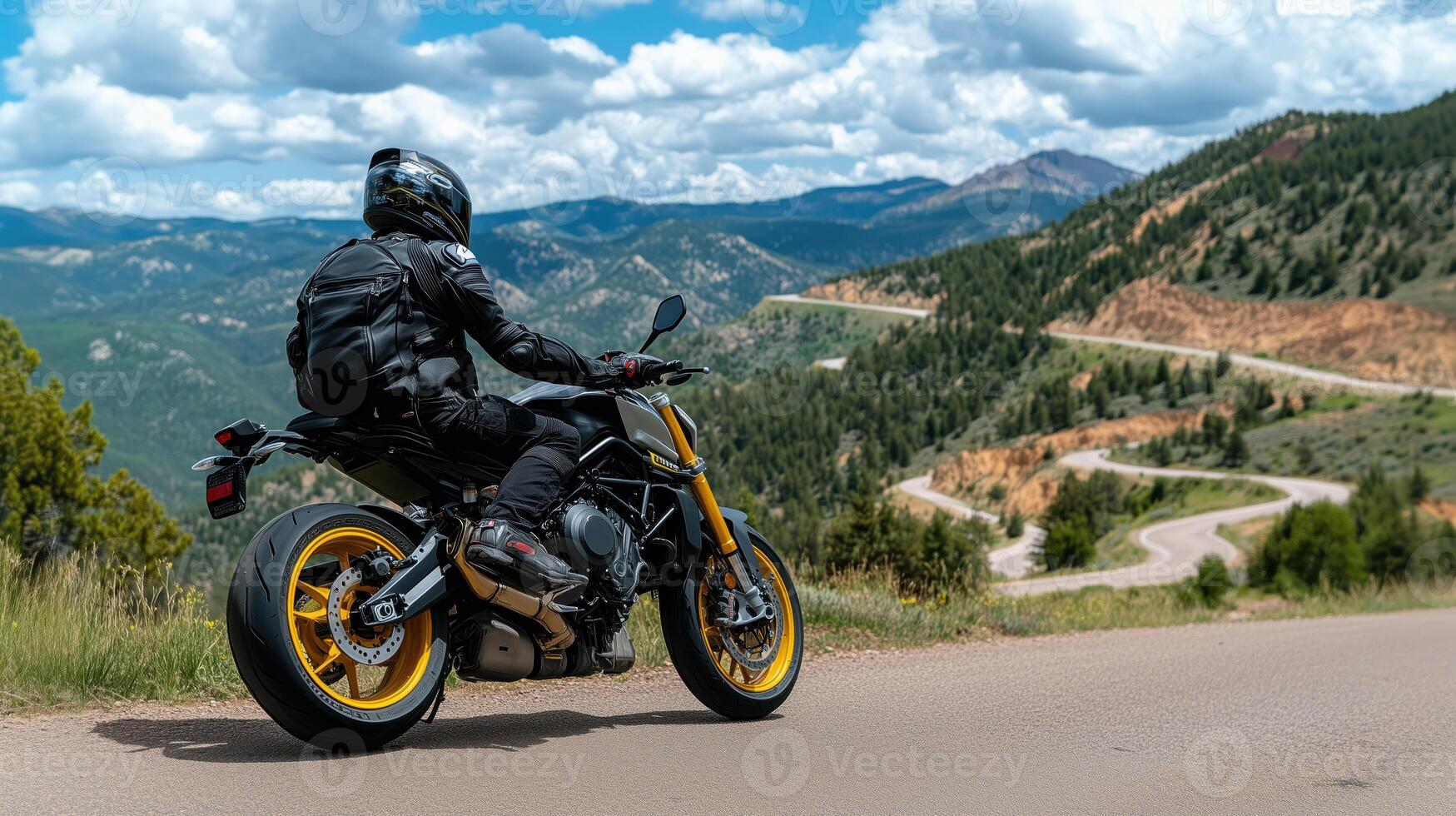 Motorcyclist in black leather gear enjoying scenic mountain views on a winding road photo
