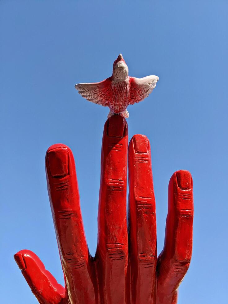 Santa Lucija, Malta - April, 2022. Red hand sculpture with bird figurine was erected to commemorate 50th anniversary of diplomatic relations between Malta and China photo
