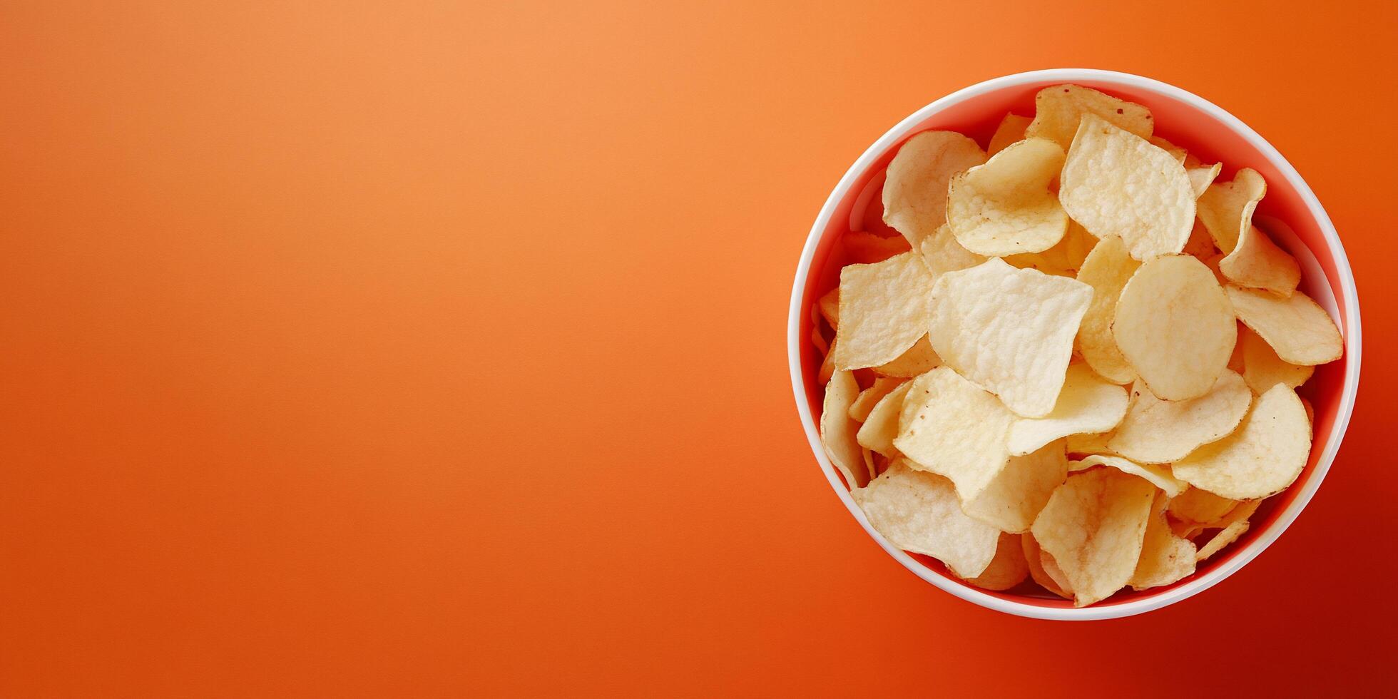 Potato chips in a bowl on an orange background photo