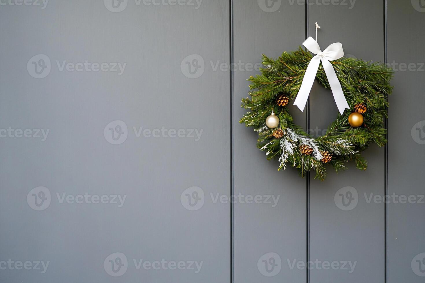 A festive wreath adorned with ornaments hangs on a gray door. photo