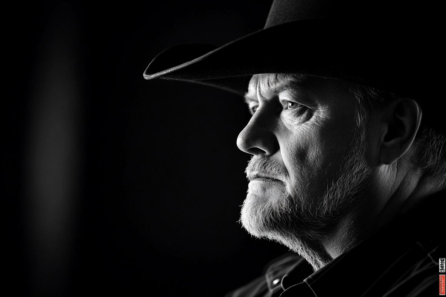 A monochrome portrait of a man in a cowboy hat, showcasing a thoughtful expression. photo
