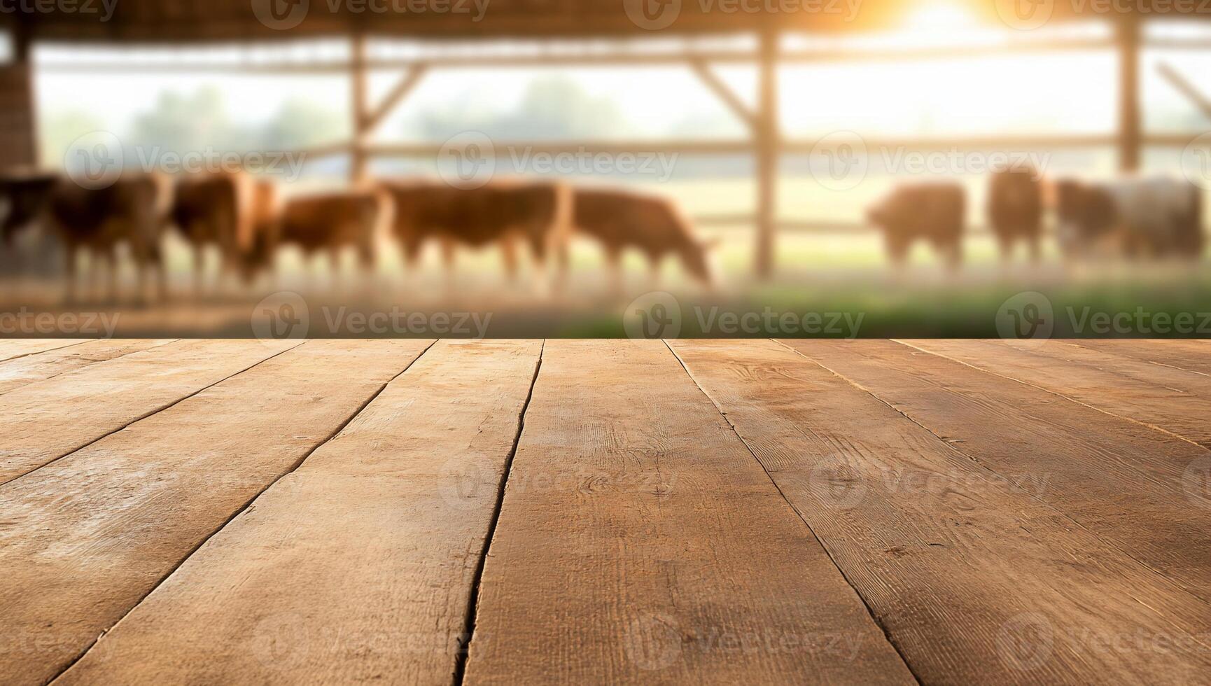 A rustic wooden table foreground with cows grazing in a barn background. photo