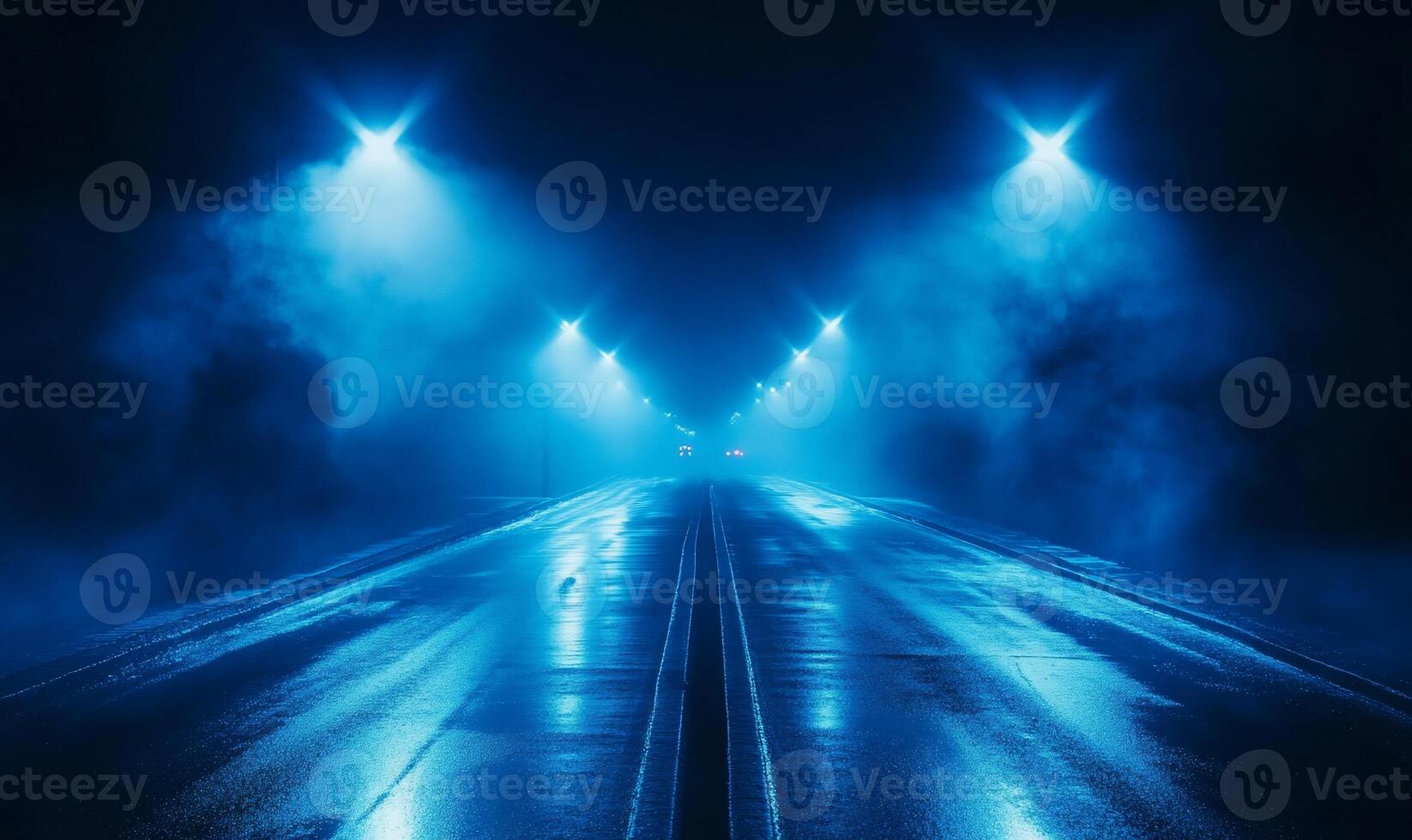 A foggy road illuminated by blue streetlights at night. photo