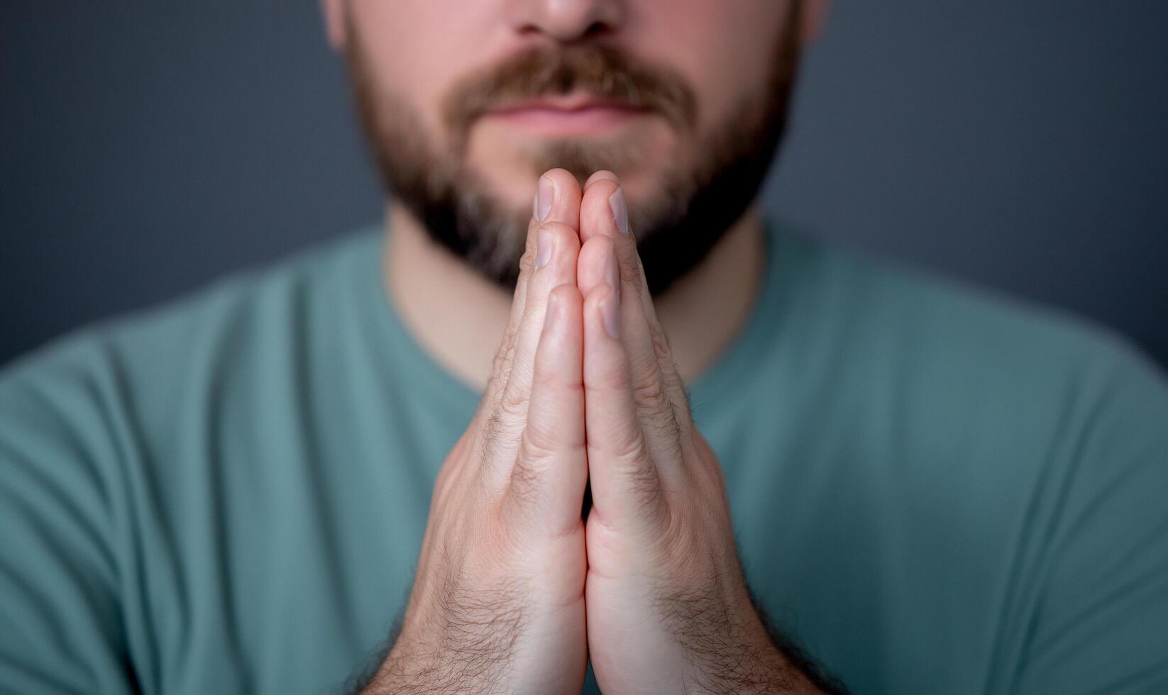 A man with hands clasped in a gesture of contemplation or prayer. photo
