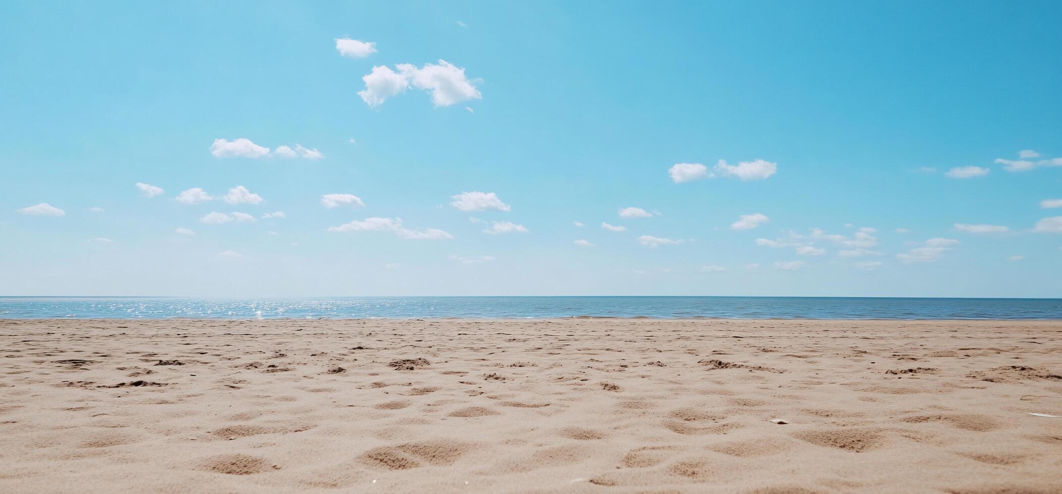 A serene beach scene with sand, water, and a clear blue sky. photo