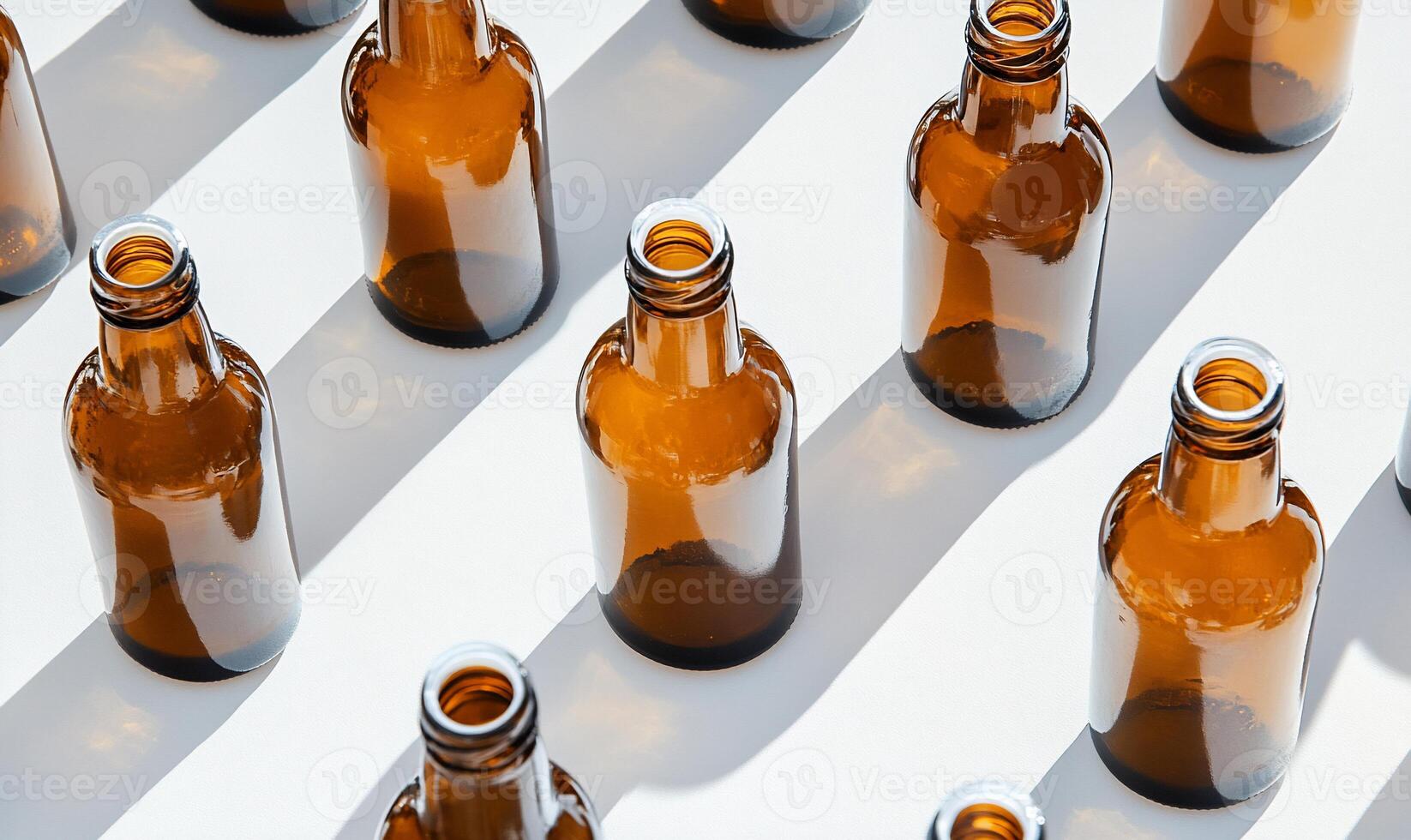 Many empty beer bottles are arranged on a white surface photo