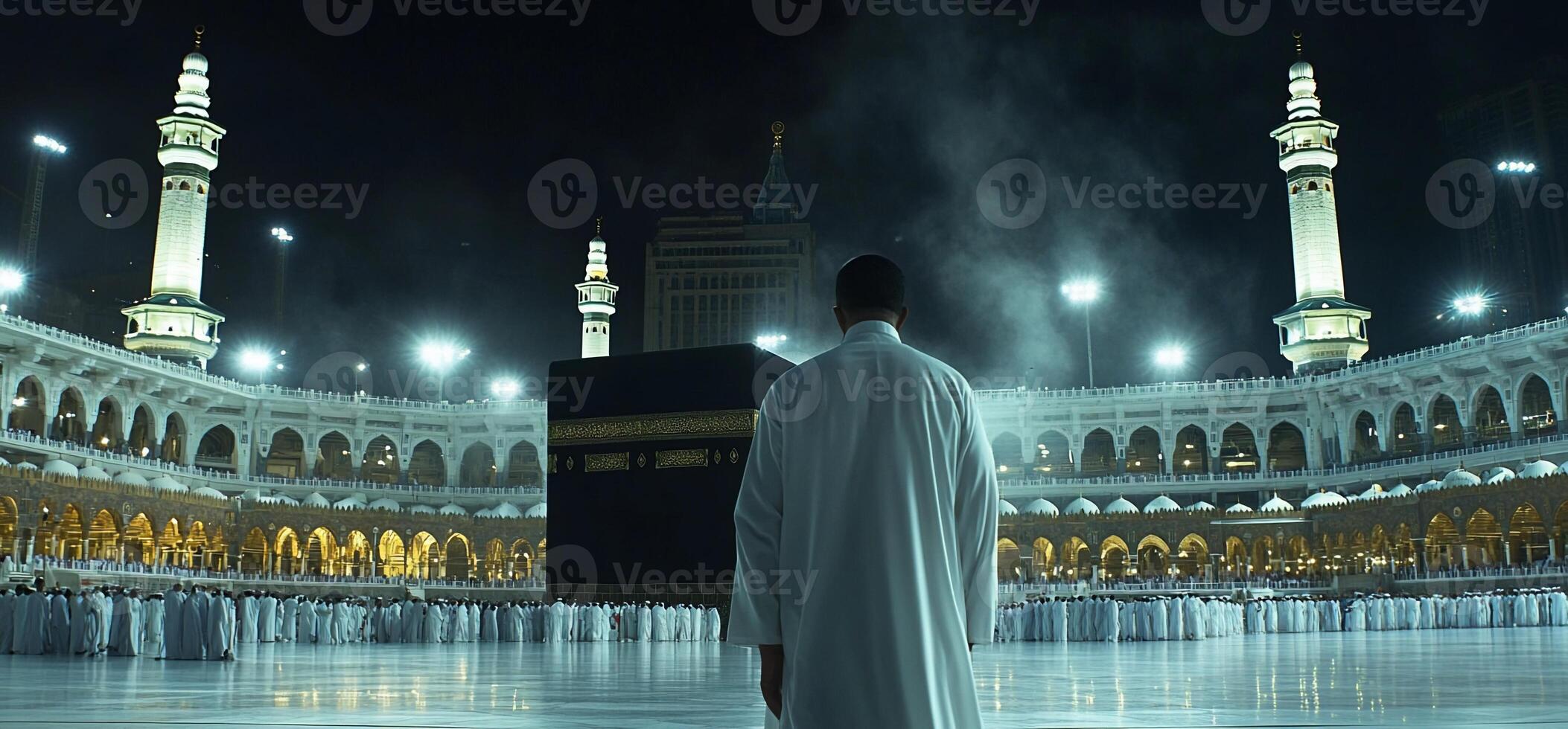 A person in white attire stands before the Kaaba in Mecca. photo