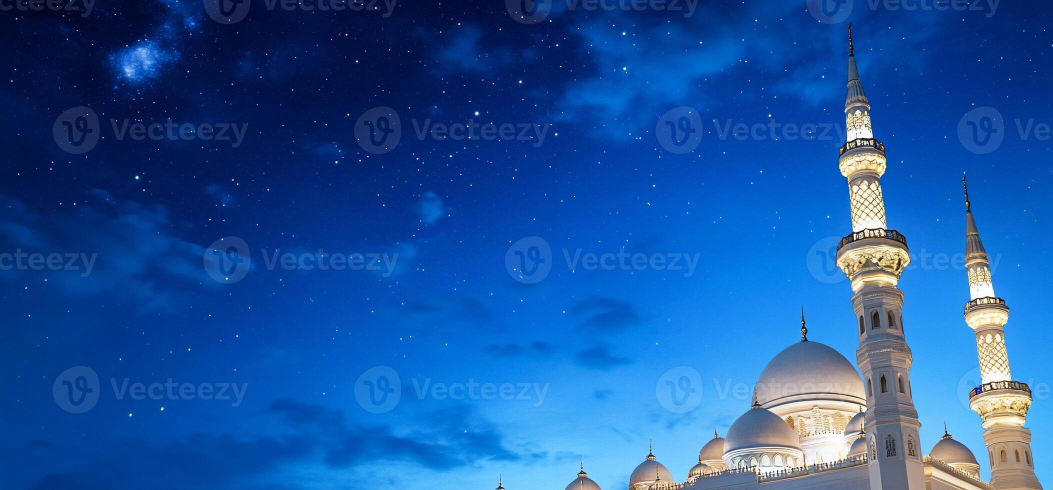 A mosque lit up at night with a blue sky photo