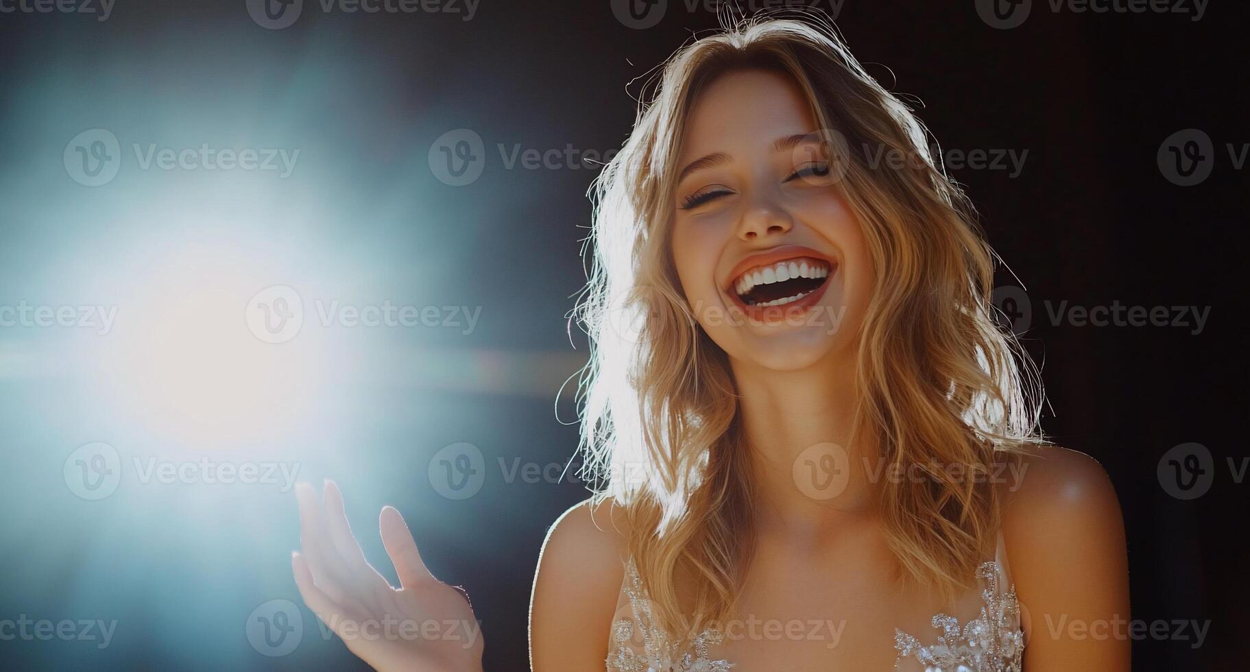 A joyful woman smiling brightly, illuminated by a spotlight. photo