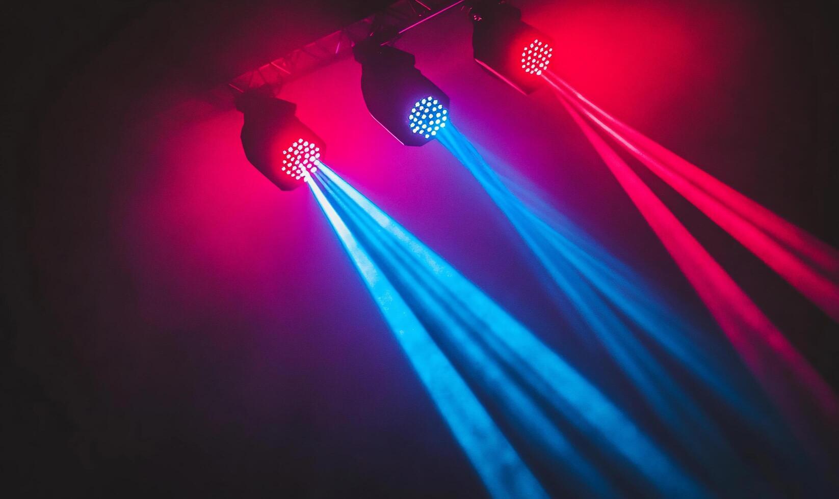 Colorful stage lights emitting beams in a dark setting. photo