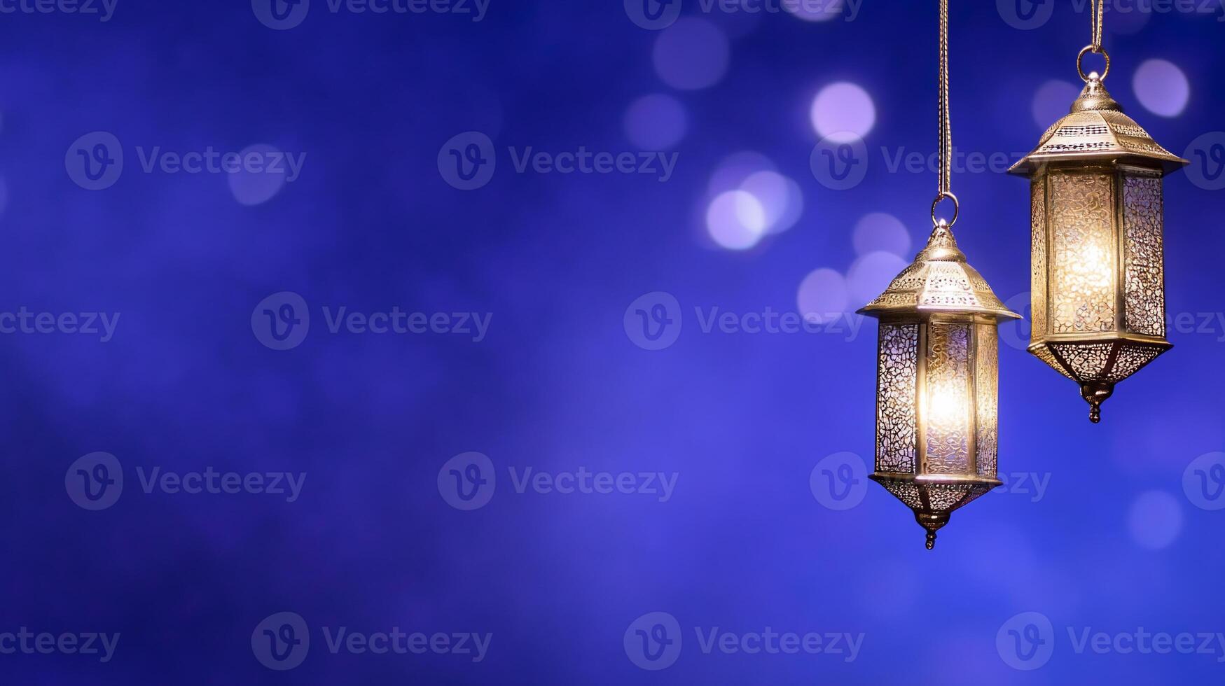 Two decorative lanterns glowing against a blurred blue background. photo