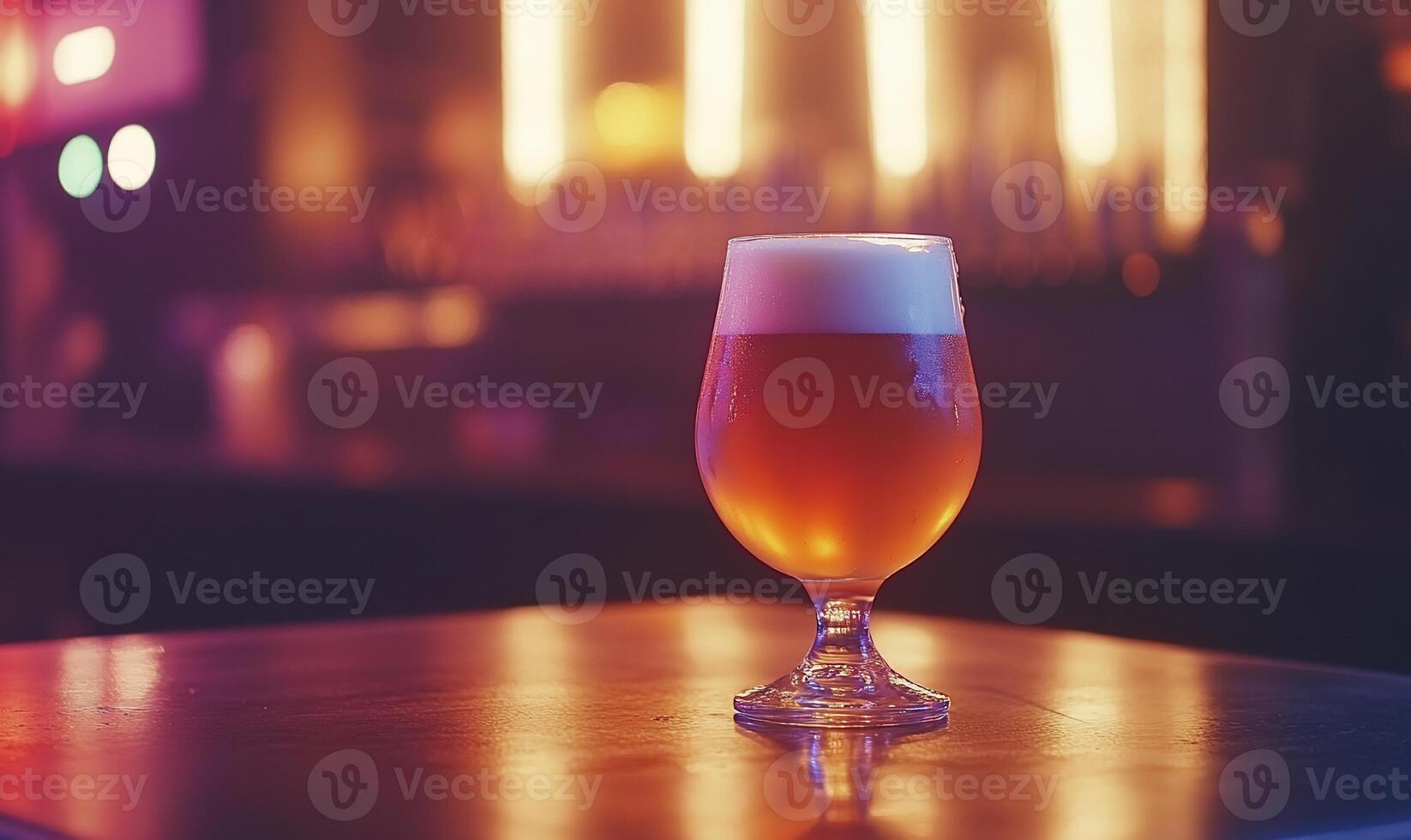 A glass of amber beer with frothy head on a bar table. photo