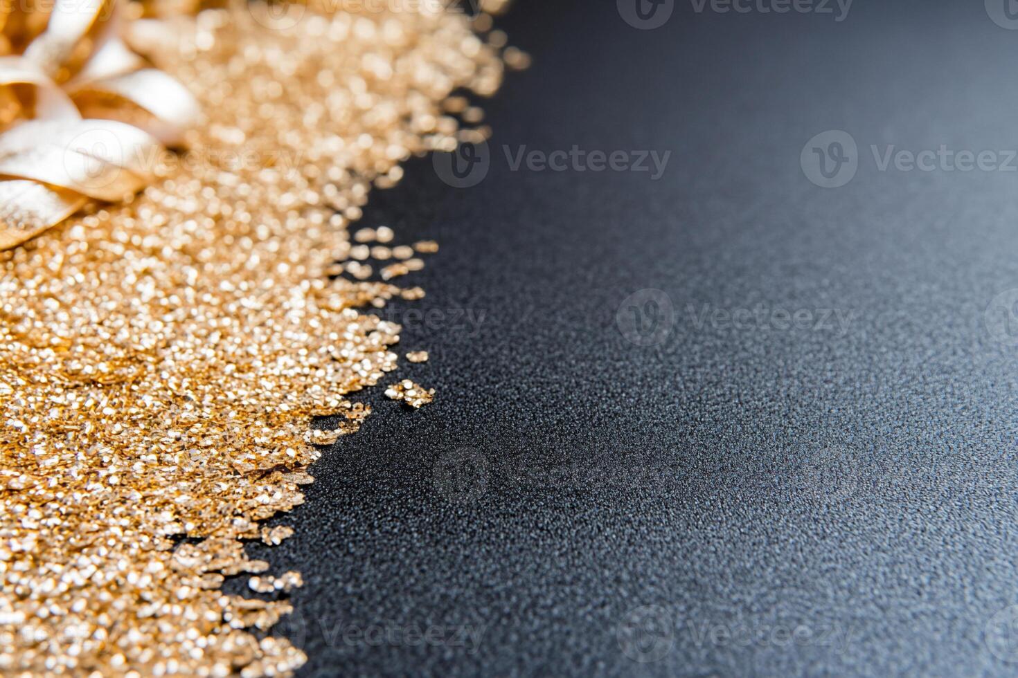 A close-up of golden glitter on a dark surface with decorative ribbon. photo
