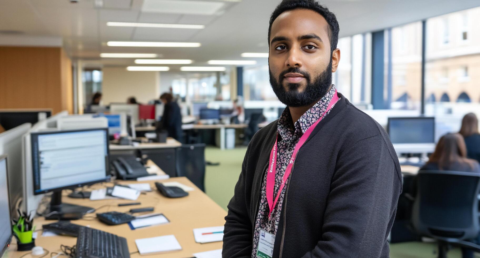 A professional man stands in an office environment, engaging with the camera. photo