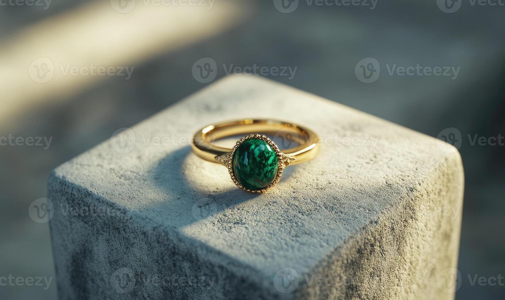 A green gemstone ring sits on a stone pedestal photo