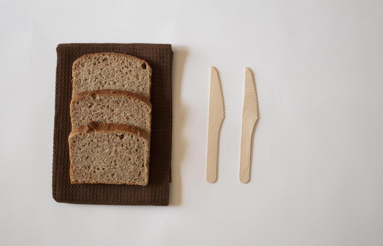 Brown bread slices with a knife on a white background minimal flat lay photo
