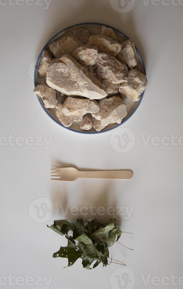 White clay stones with green leaves and a fork on a white background photo