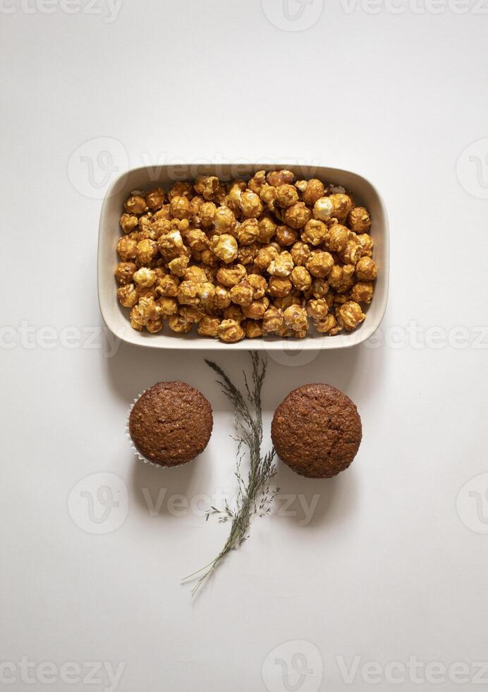 Chocolate cupcakes and caramel popcorn on a white background flat lay photo