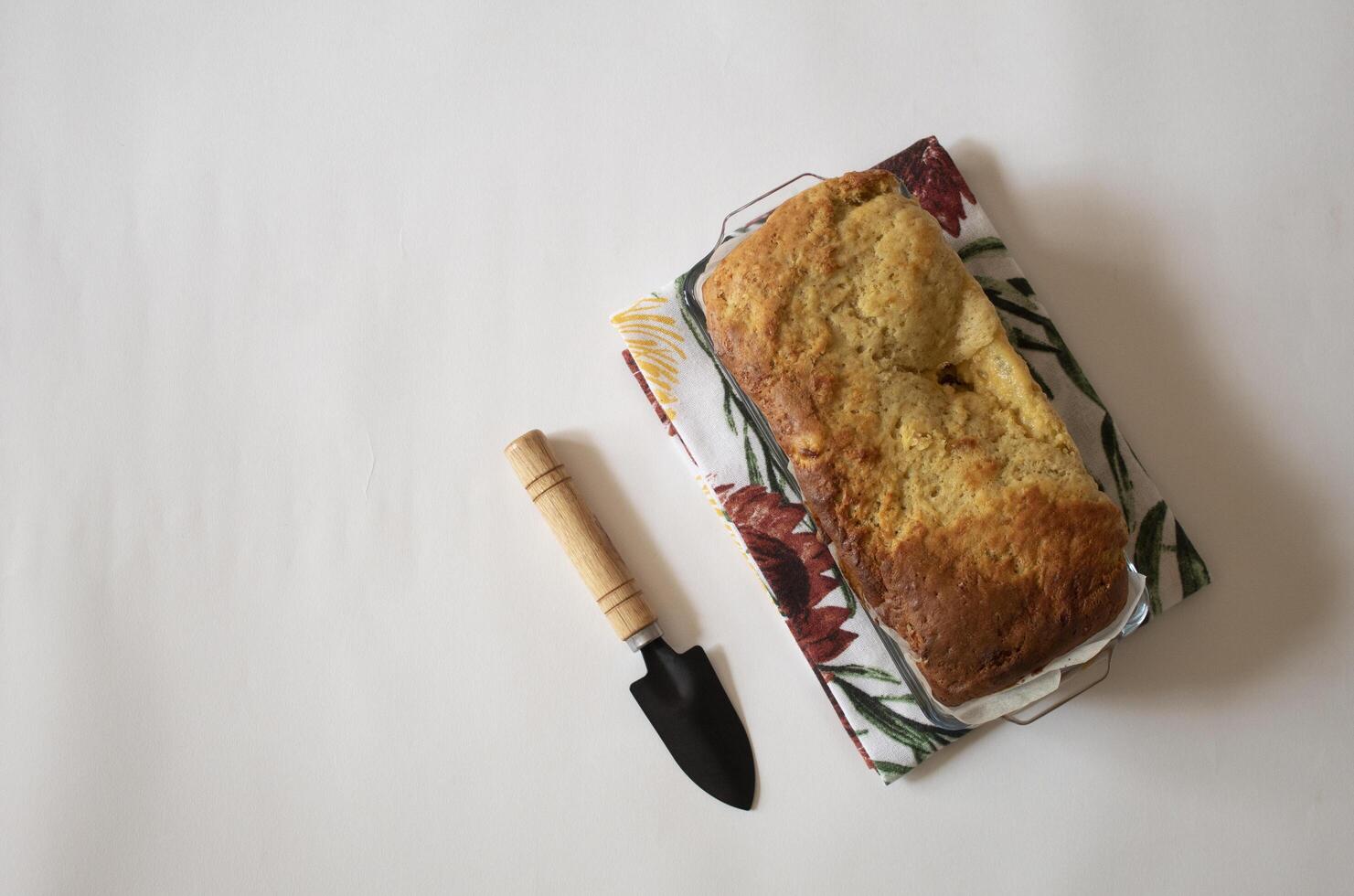 Banana bread next to a small shovel on a white background flat lay photo