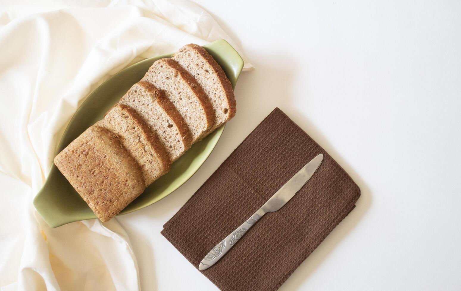 Brown bread slices with a knife on a white background flat lay photo