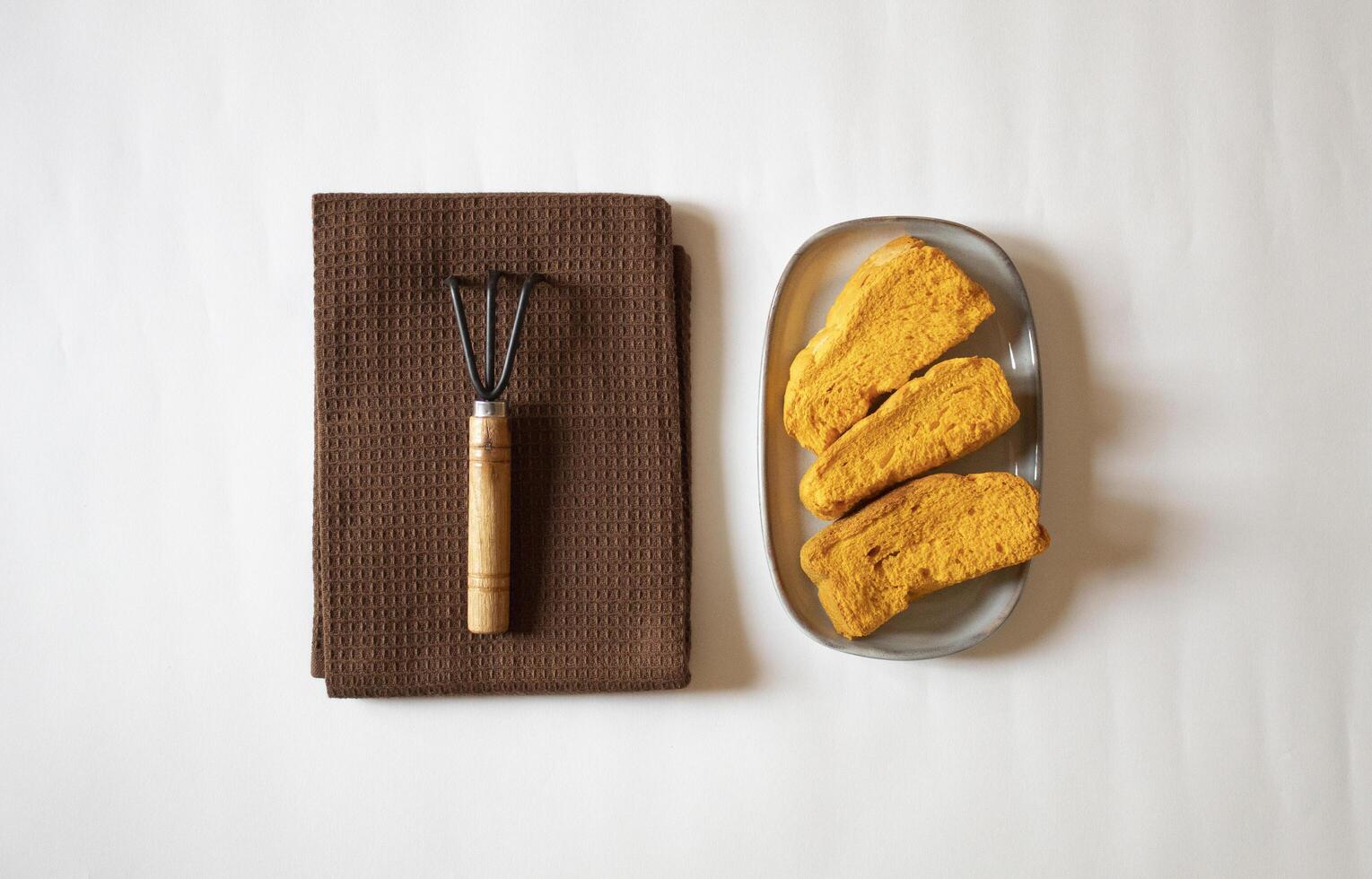 Yellow rusks with a small garden fork minimal flat lay photo