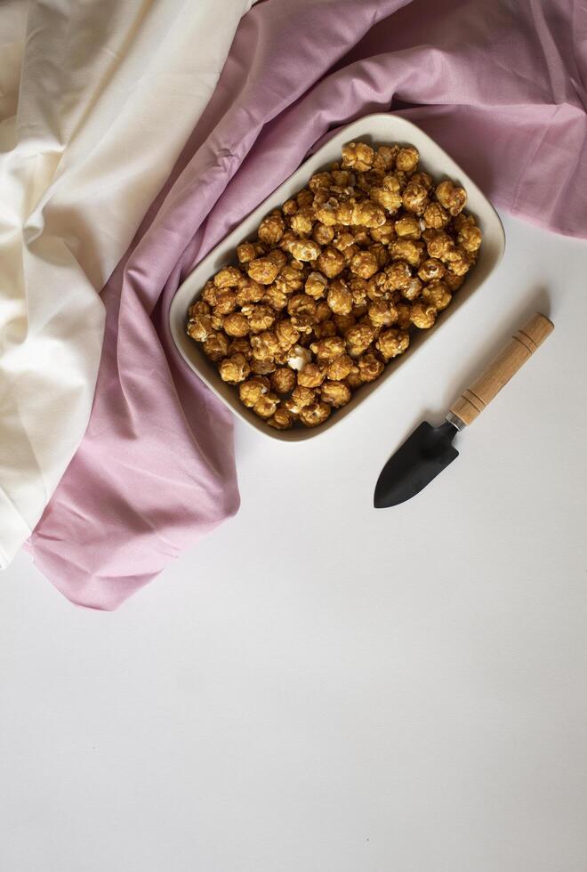 Caramel popocorn with a small shovel on a white background photo