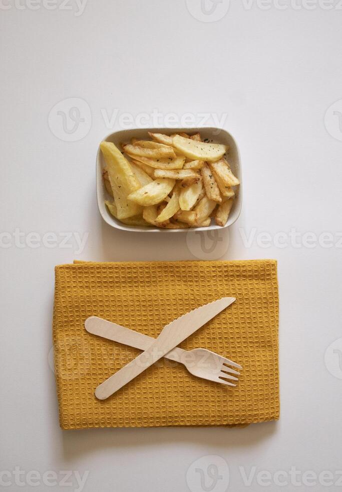 French fries on a plate next to a fork and a knife on a white background photo