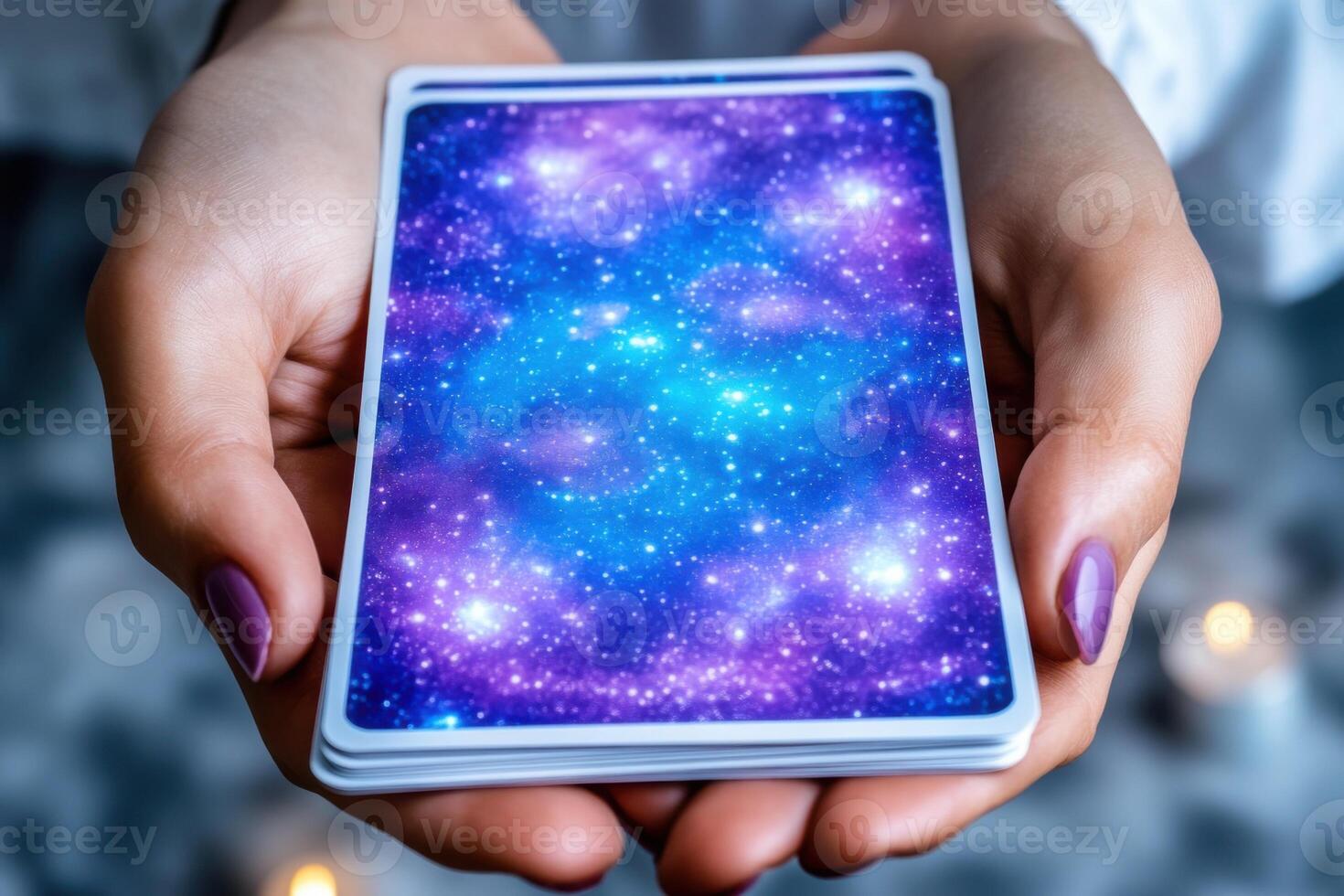 Mystical tarot card deck surrounded by glowing blue and purple energy patterns held in dim candlelight for spiritual exploration photo