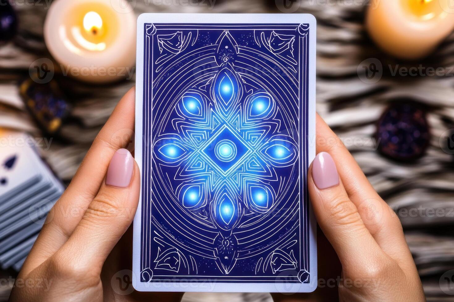 Mystical tarot card deck with glowing blue and purple patterns held in hands during candlelit spiritual session photo