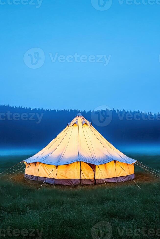 Abandoned carnival tent stands alone in a foggy field at night creating a mysterious and eerie atmosphere photo