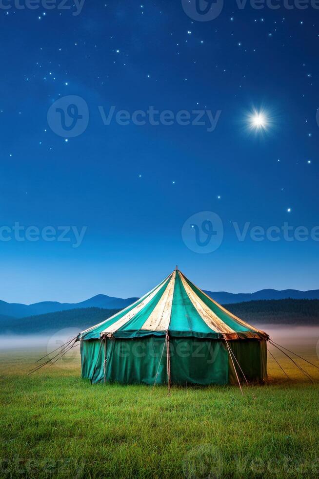 Mysterious abandoned carnival tent in foggy field under starry night sky photo
