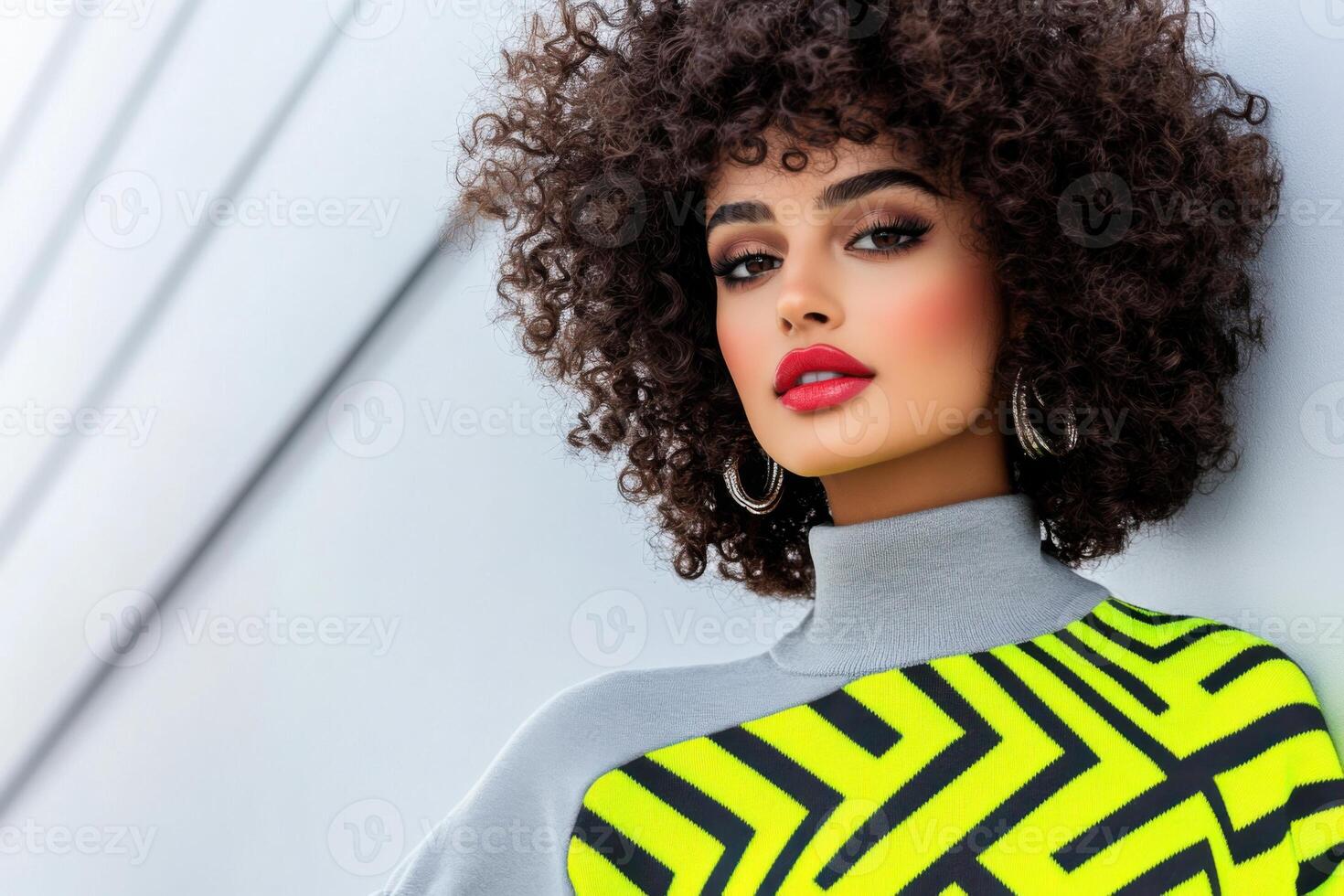 Stylish woman in a minimalist grey sweater with neon chevron patterns poses against a white urban backdrop blending casual and futuristic aesthetics in a sunny urban setting photo