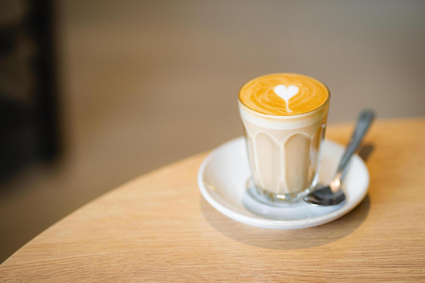 Top view of hot latte coffee with latte art in a white cup on wooden table photo