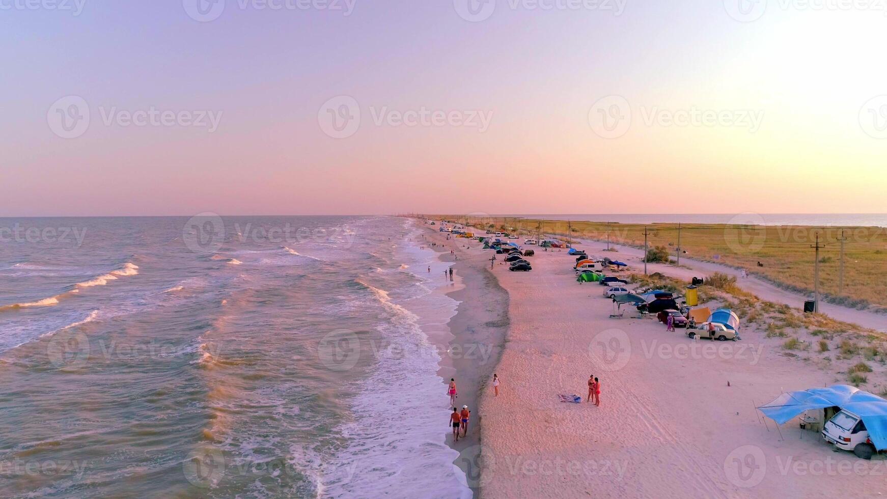 Campsite on sea spit, view above from drone, sunlight and people resting on beach photo