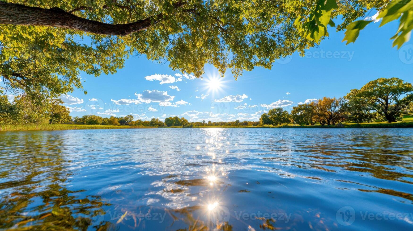 Serene sunrise illuminating a calm lake surrounded by lush greenery and clear blue skies photo