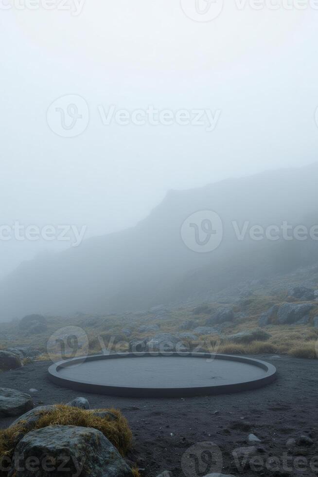 A circular platform on a rocky hill with sparse vegetation, shrouded in thick fog, creating a mysterious and ethereal atmosphere photo