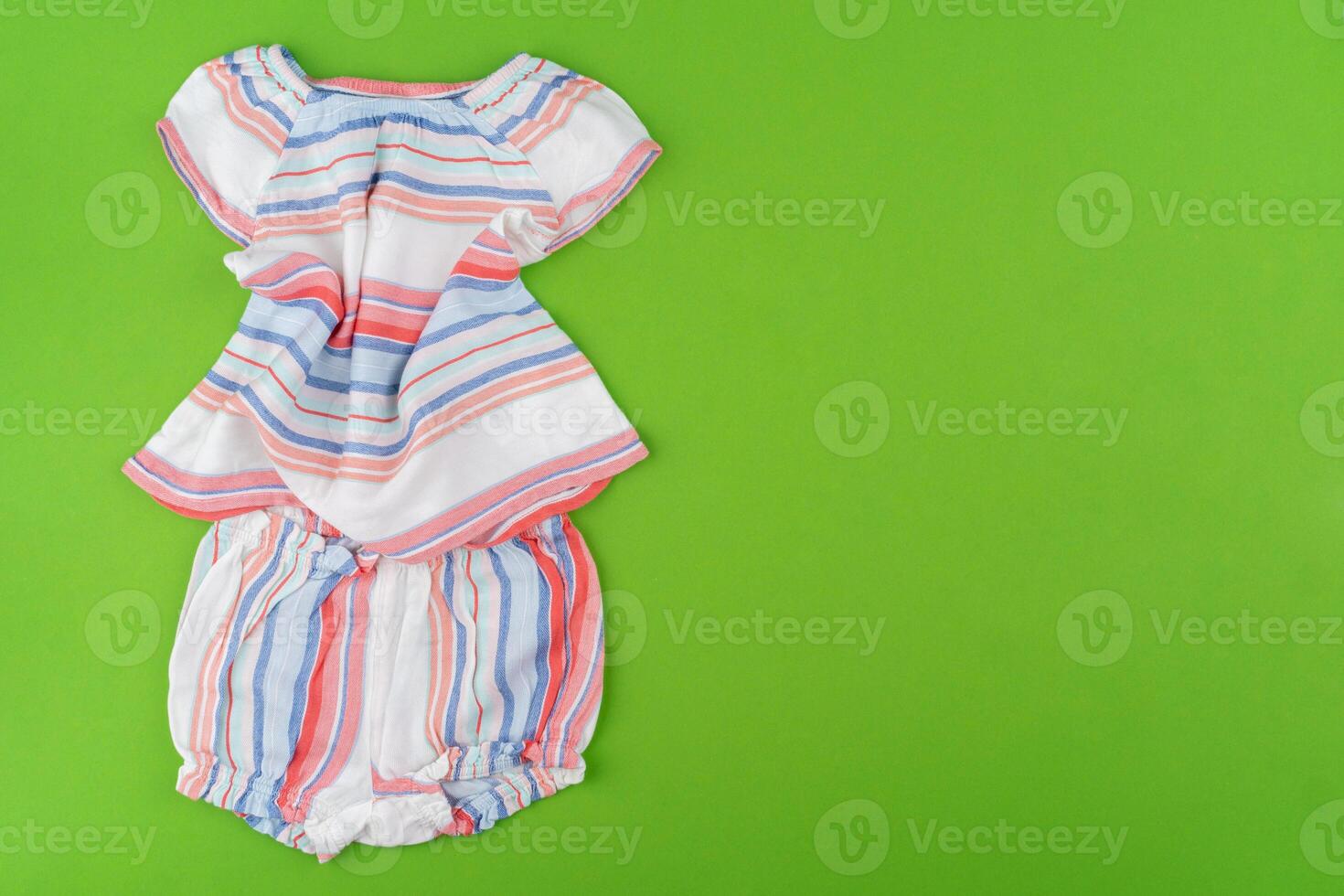 Top view of baby clothes on green background photo