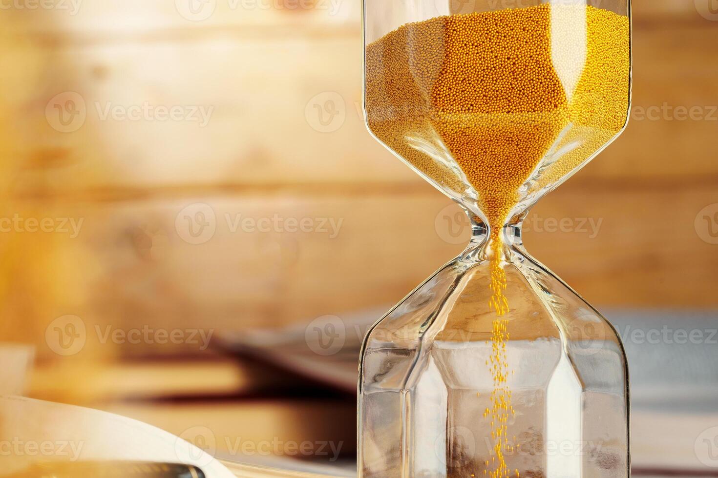 Hourglass with sand close up on wooden background photo