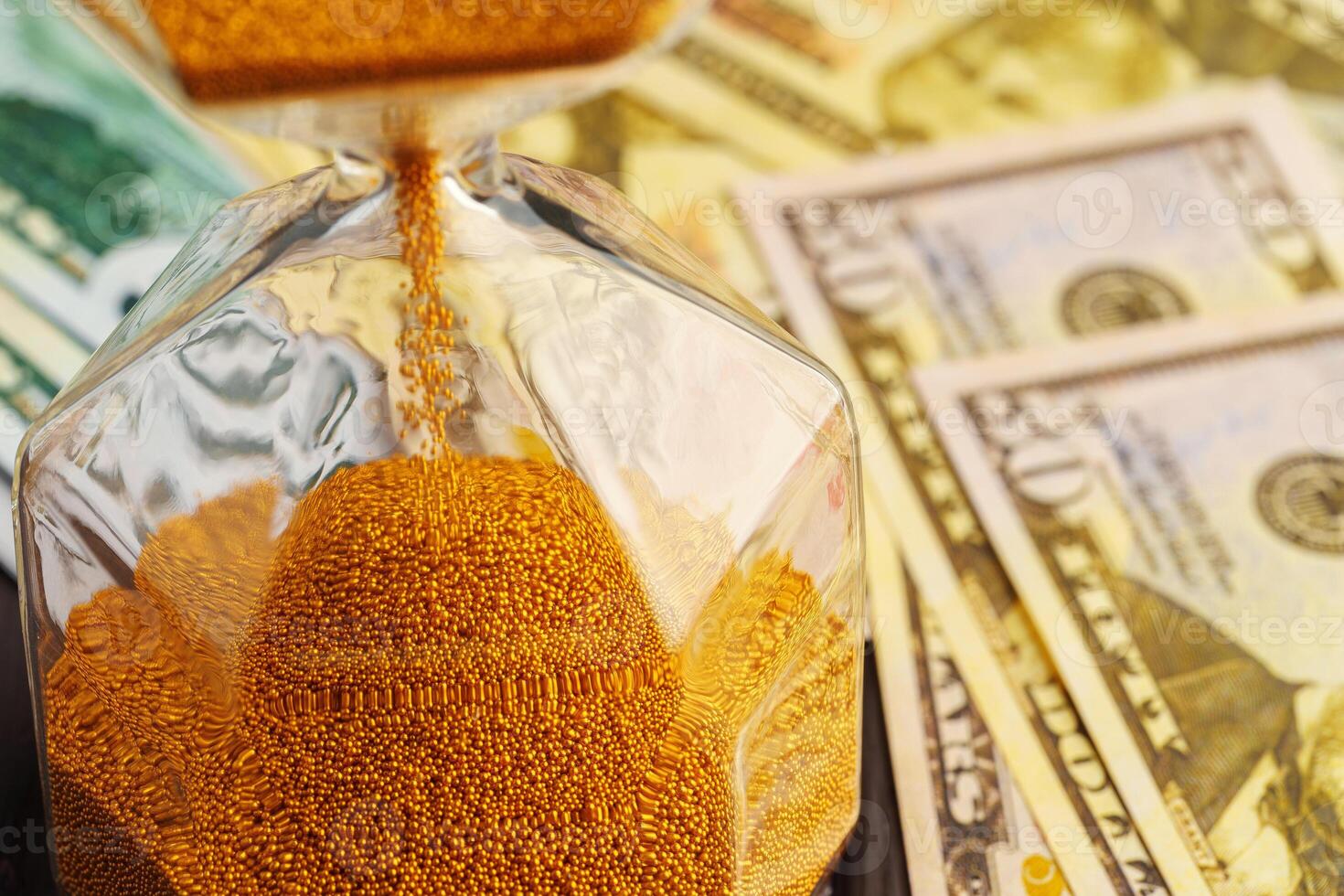 Hourglass on stack of dollar banknotes close up photo