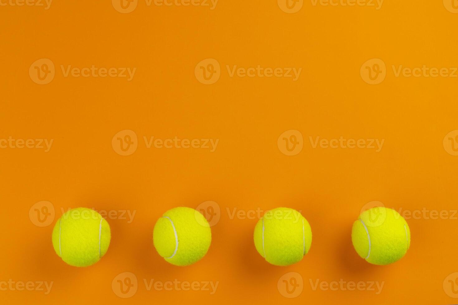 Four tennis balls on an orange background photo