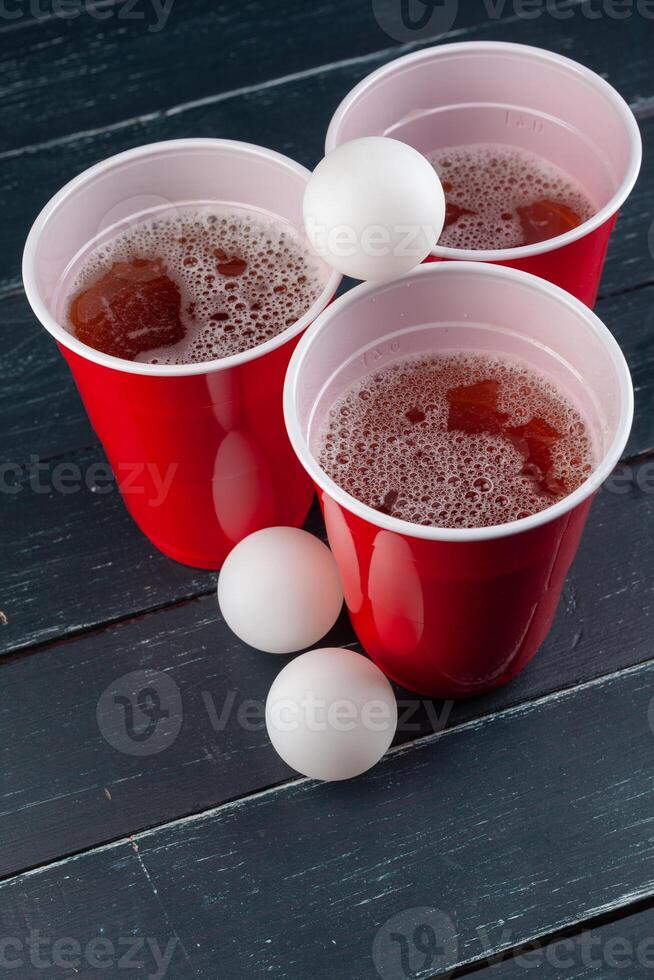 Wooden table with red cups and ball for beer pong photo