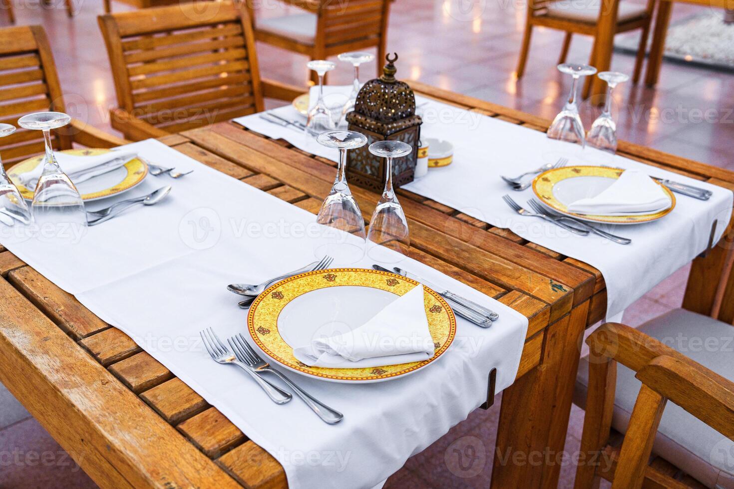 Elegant dining setup in an outdoor restaurant with wooden furniture and delicate tableware during a sunny afternoon photo