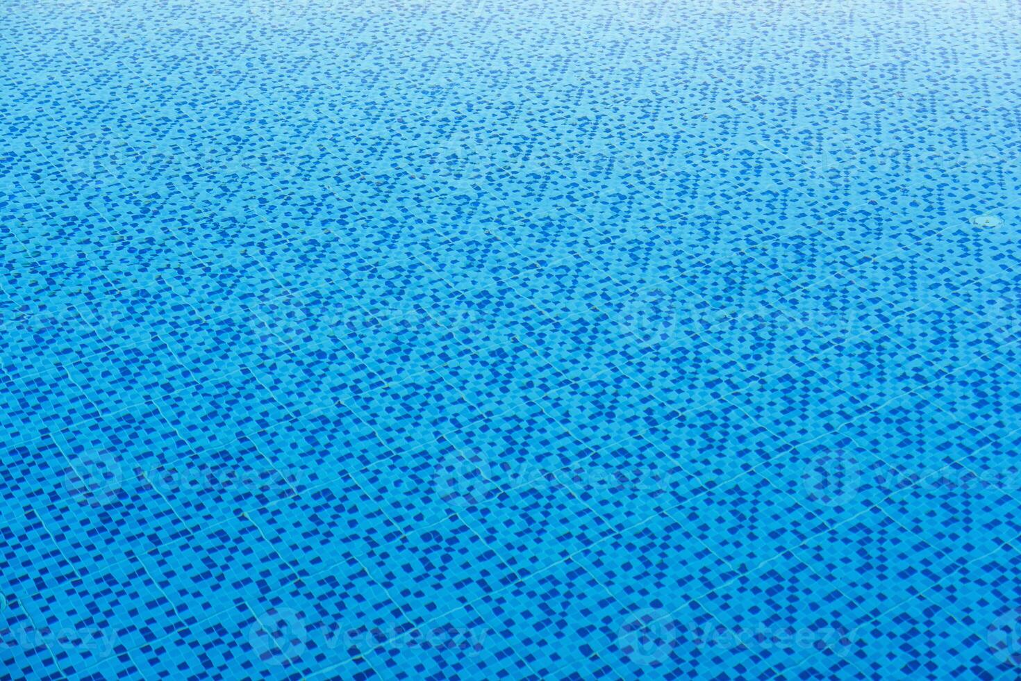 Mosaic tiles create a beautiful abstract pattern in a sunny blue swimming pool photo